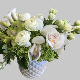 White and green floral arrangement in a textured white vase