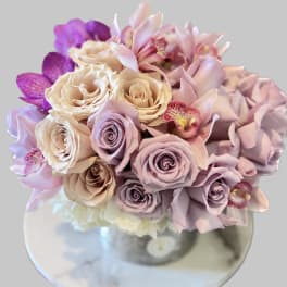 Bouquet of pastel roses and orchids in a clear vase