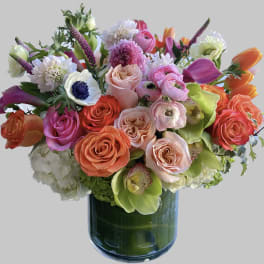 Mixed bouquet of roses, calla lilies, and orchids in a glass vase