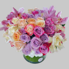 Bouquet of pink, lavender, and cream roses in a green glass vase
