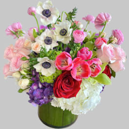 Mixed bouquet of pink, white, red, and purple flowers in a green glass vase
