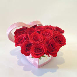 Heart-shaped box of red roses with a pink handle