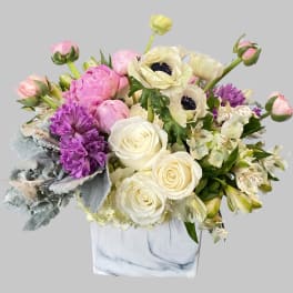 Mixed pink, white, and purple flowers in a square marble vase