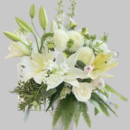 White lilies and roses arranged in a clear glass vase