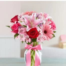 Pink and red mixed bouquet in a glass vase with a pink ribbon