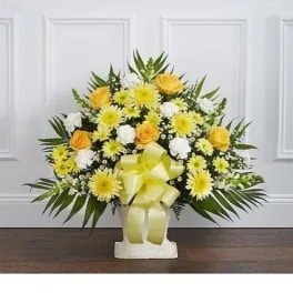 Yellow and white floral arrangement in a white vase with a ribbon