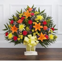 Standing floral spray with orange lilies and mixed bright blooms