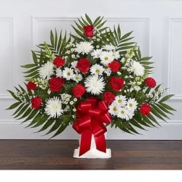 Standing floral spray with red roses and white daisies on a white easel