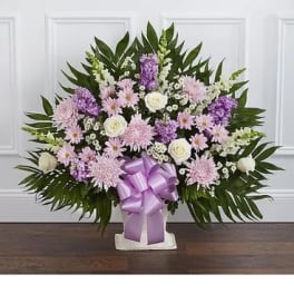 Lavender and white floral spray with a purple ribbon on a stand