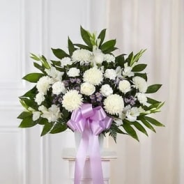 White funeral spray with a lavender ribbon on a stand