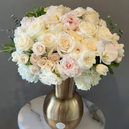 White rose and orchid arrangement in a gold vase