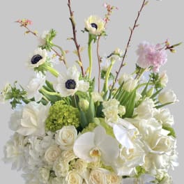 White floral arrangement with orchids, roses, and tulips in a vase