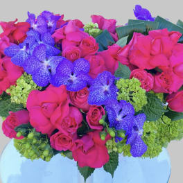 Pink roses and purple orchids arranged in a vase