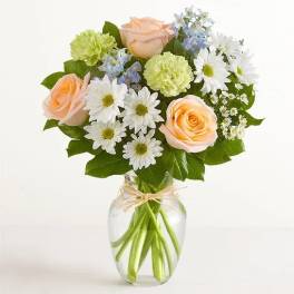 Peach roses and white daisies in a clear glass vase