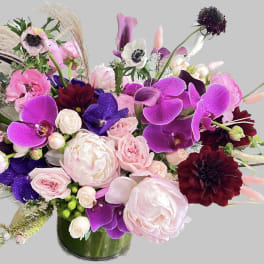 Pink, purple, and burgundy floral arrangement in a glass vase