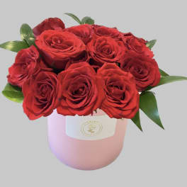 Red roses arranged in a pink hatbox