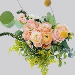 Peach and blush roses with yellow accents in a loose bouquet