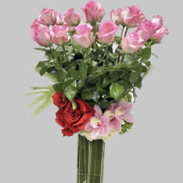 Tall bouquet of pink and red roses with orchids in a clear glass vase