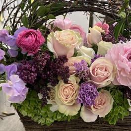Basket arrangement of pink and lavender roses with peonies and lilac