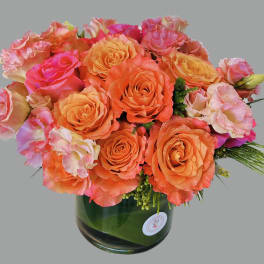 Bouquet of orange and pink roses in a green glass vase