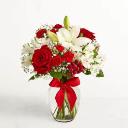 Red roses and white lilies in a glass vase with a red ribbon