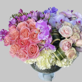 Bouquet of pink roses and purple orchids in a glass vase