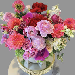 Mixed bouquet of pink, red, and white flowers in a decorative vase