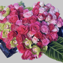 Heart-shaped bouquet of pink roses with green orchids and dark leaves