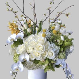 White roses, orchids, and tulips in a white vase