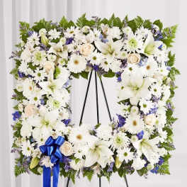 White floral standing wreath on an easel with a blue ribbon