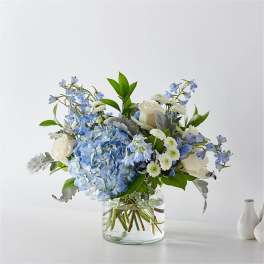 Blue hydrangea and white rose bouquet in a clear glass vase