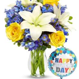 Bouquet of white lilies, yellow roses, and blue flowers in a glass vase with a Father's Day balloon