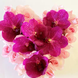Pink roses with magenta orchids in a compact bouquet