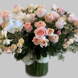 Large bouquet of pale pink roses and white orchids in a glass vase