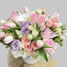 Bouquet of pink, lavender, and white flowers in a white vase