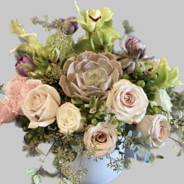 Bouquet of pale roses and green orchids in a light blue vase