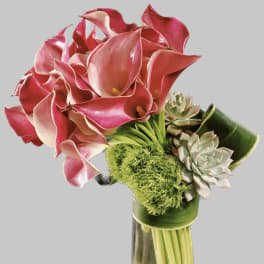 Pink calla lilies and succulents in a tall glass vase