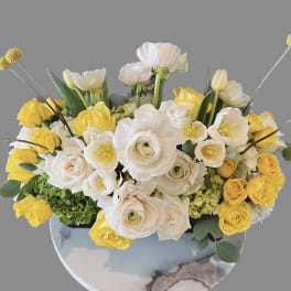 Yellow and white floral arrangement in a round vase