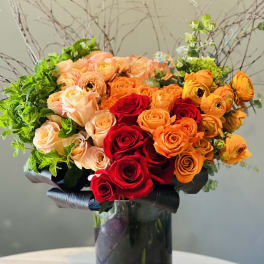 Bouquet of red, orange, and peach roses in a black vase