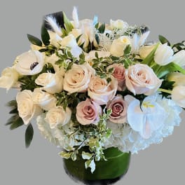 Bouquet of white and blush roses with white orchids in a green vase