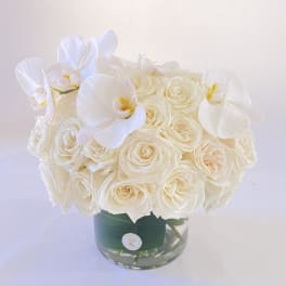 White rose bouquet with white orchids in a glass vase