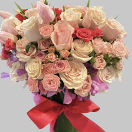 Bouquet of pink and cream roses with tulips tied with a red ribbon