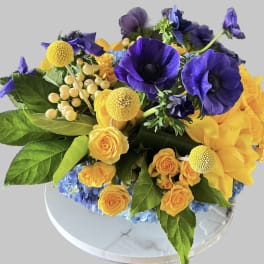 Purple anemones and yellow roses in a low round arrangement