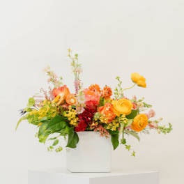Bright mixed flower arrangement in a white box vase