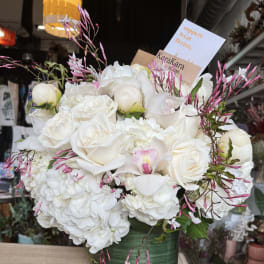 White roses and hydrangeas in a green glass vase with pink accents