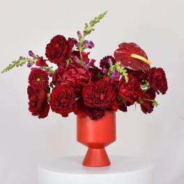 Red floral arrangement in a red vase with anthurium and roses