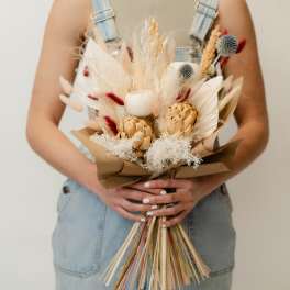 Dried bouquet with beige, white, and red accents wrapped in brown paper
