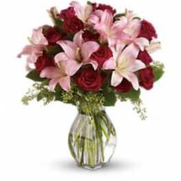 Bouquet of pink lilies and red roses in a clear glass vase