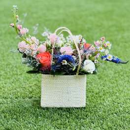 Mixed flower arrangement in a woven basket on grass