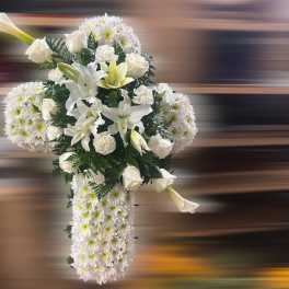 Tall white floral cross arrangement with lilies, roses, carnations, and mums